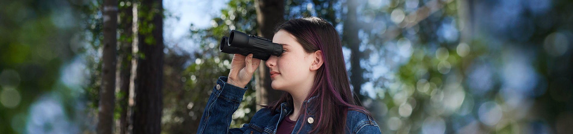  a girl in the woods looking through binoculars 