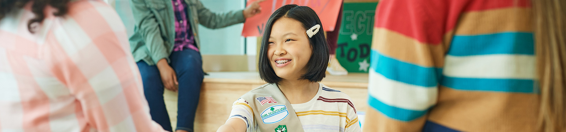  A Senior Girl Scout smiling at her two friends whose backs are to the camera 