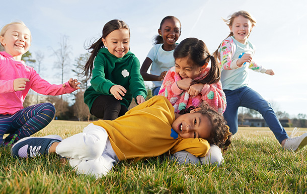 Group of Daisy Girl Scouts playing and laughing outdoors