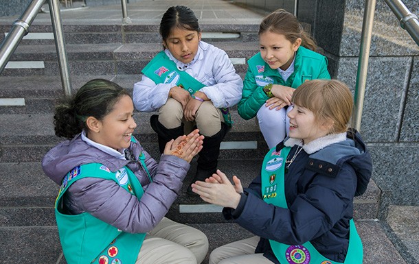 Four Junior Girl Scouts sitting outdoors playing games