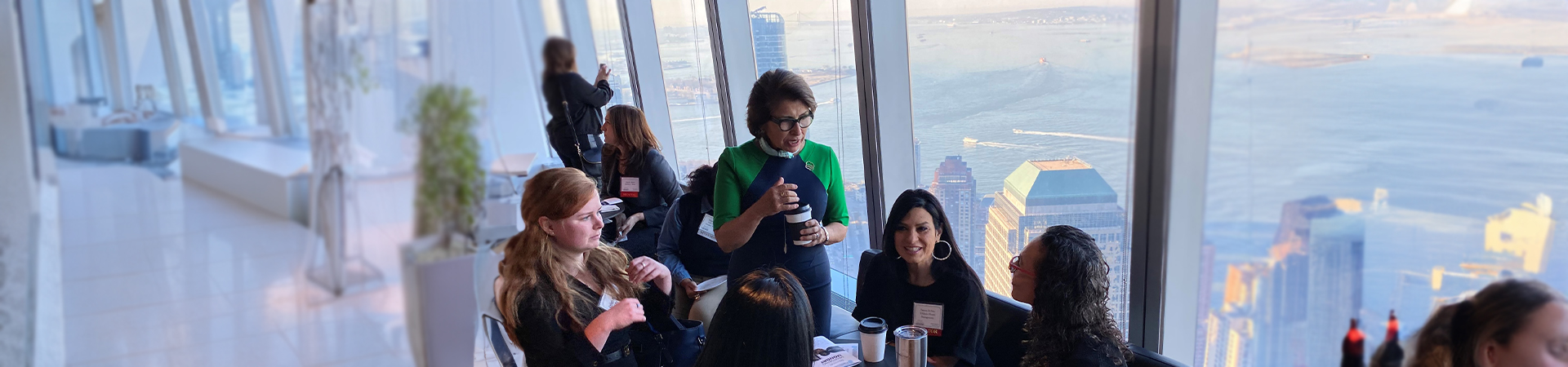  Former Girl Scout CEO Sylvia Acevedo talks to a group of women while they all drink coffee 