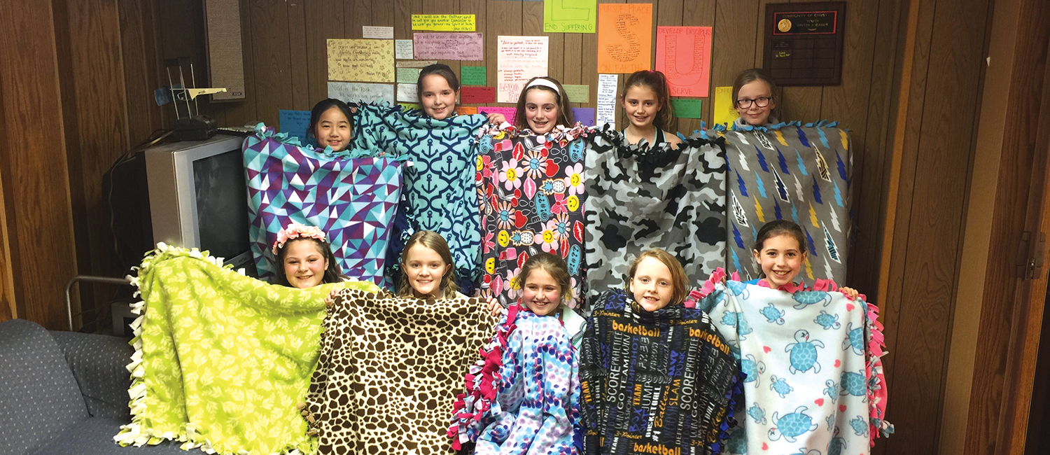  A group of Girl Scouts holding up no sew fleece blankets 