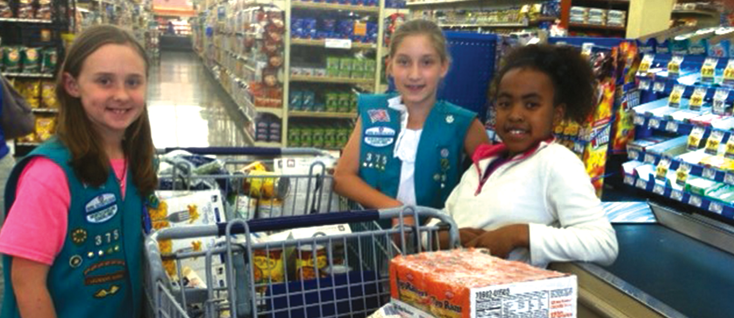  Three Junior Girl Scouts with two shopping carts full of food 