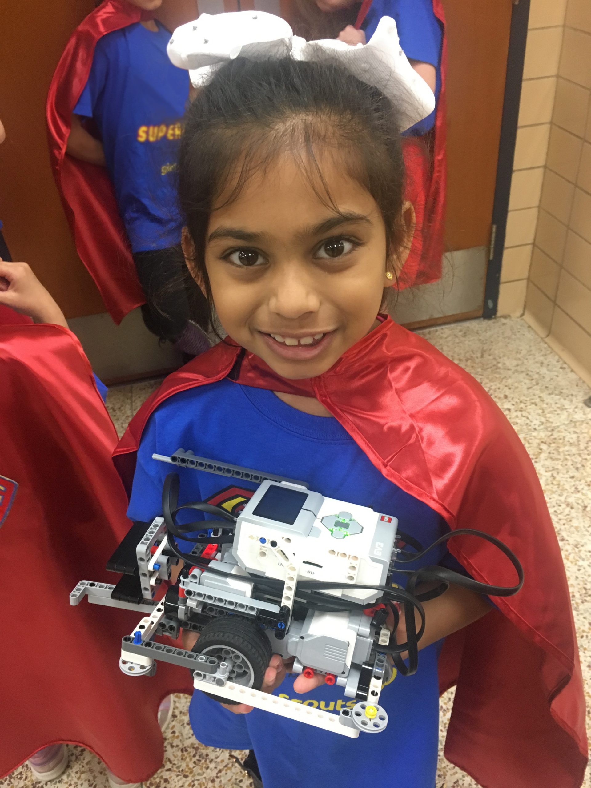 Supergirl Pari proudly holds one of her team's robots.