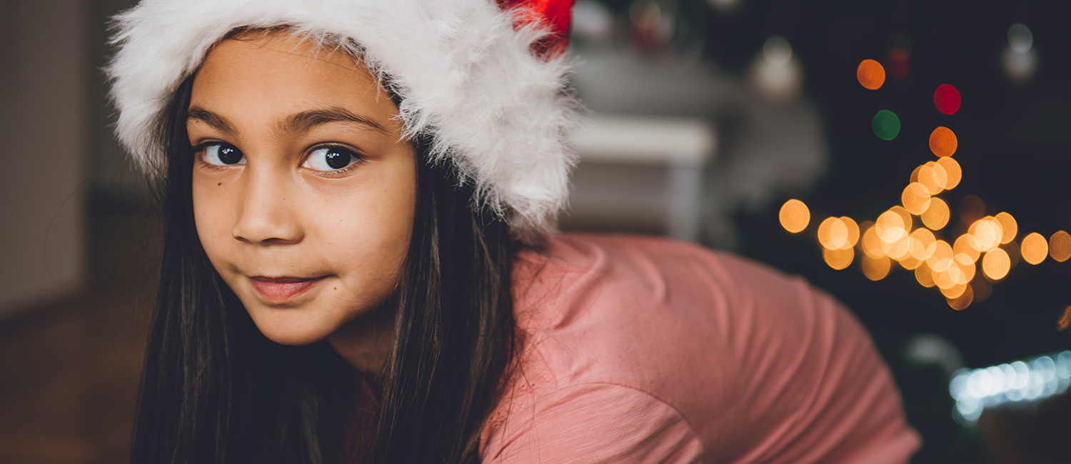  Festive girl wearing Santa hat enjoys gifts for girls. 