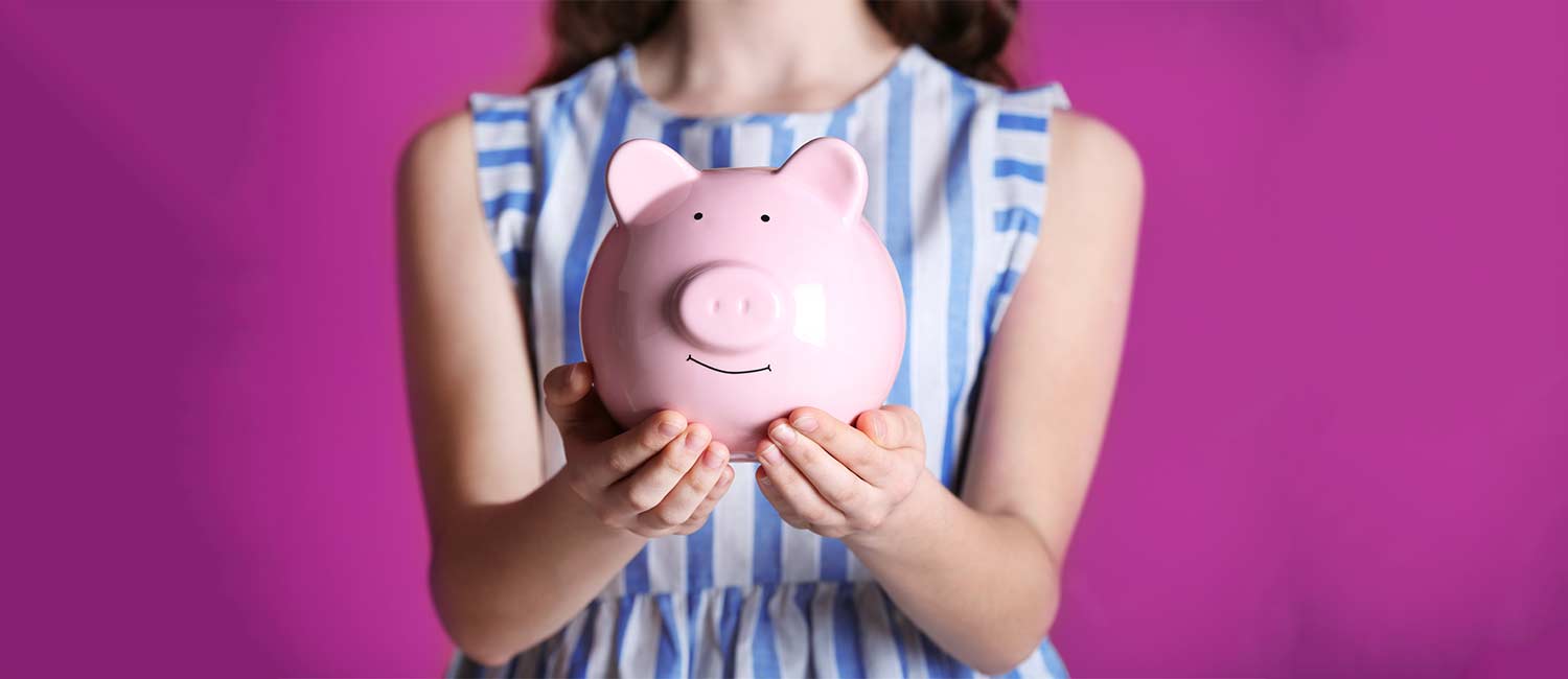  Girl holding a pink piggy bank with both hands. 
