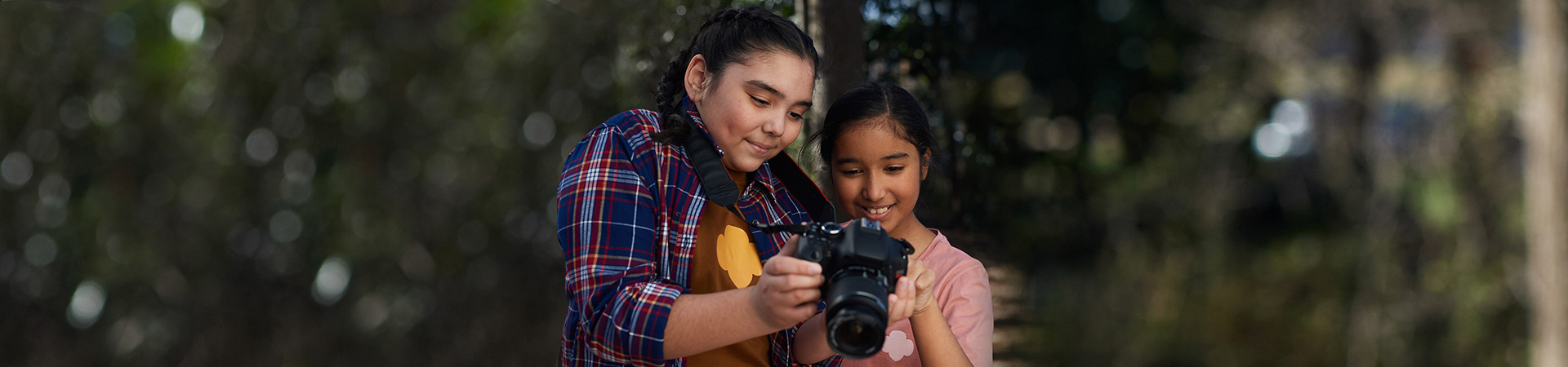  an older Girl Scout showing a younger girl a photo she took on a camera 