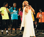 Photo of Melinda Carroll singing with Girl Scouts on stage. © GSUSA. All rights reserved