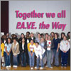 Photo of girls on stage with sign saying "Together we all P.A.V.E. the Way." &copy; GSUSA. All rights reserved.