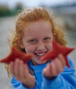 Photo of a girl holding starfish. &copy; GSUSA. All rights reserved. (Photographer: Lori Adamski-Peek)