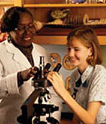 Photo of a Girl Scout and adult looking through a microscope.