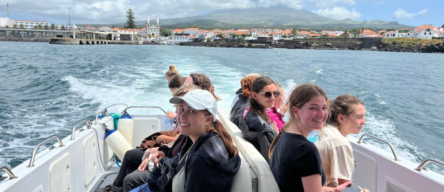 teenage girls sitting on a small speedboat with historic port in the background
