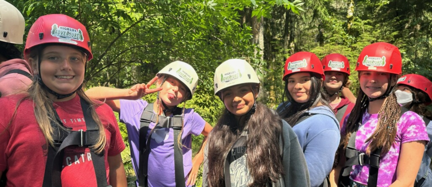 a group of smiling teen girls wearing helmets and harnesses