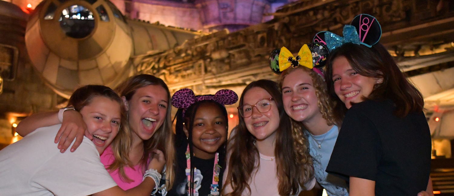a group of teen girls smiling and wearing mouse ears 