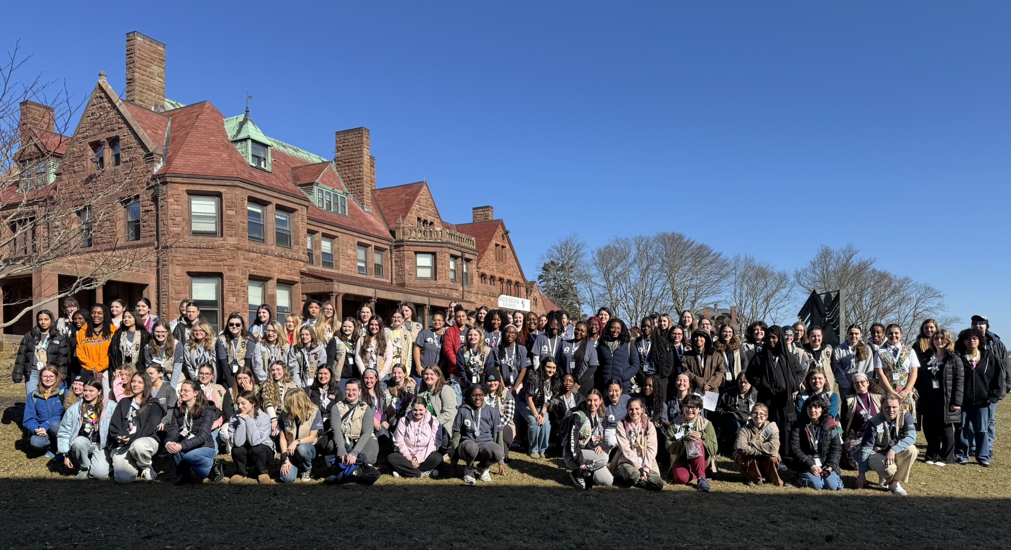 seven teenage girls standing on a stage with papers and a microphone