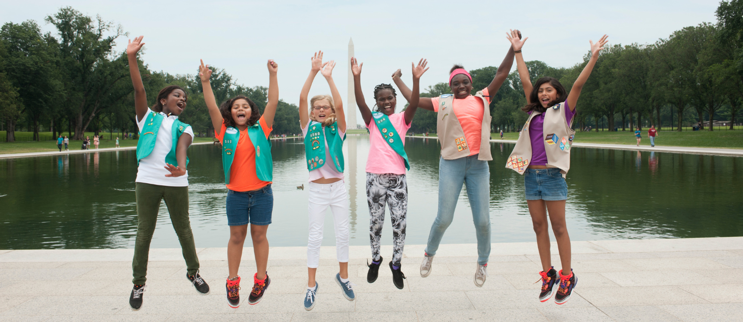a group of Girl Scouts jumping in front of the Washington Monument in Washington, D.C.