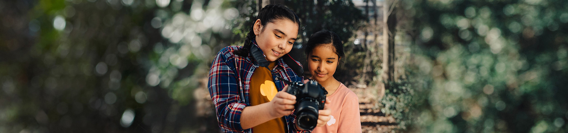  Two young Girl Scouts outside with professional photo camera nature photography badge activity. 