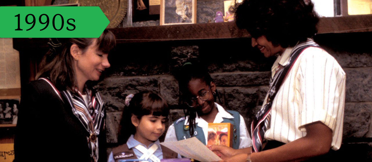 Girl Scout volunteers teach a Girl Scout Brownie and Girl Scout Junior about the Girl Scout Cookie sale, circa 1990s.    