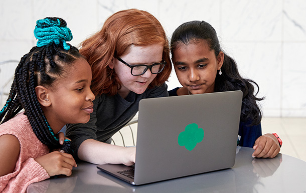 Three Girl Scouts sitting around a laptop at a table