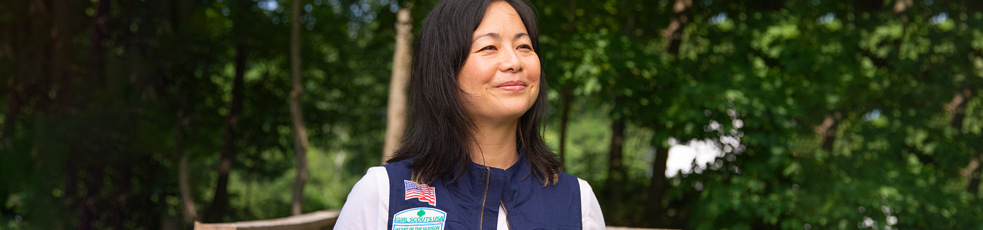  Adult volunteer wearing vest outside smiling. 