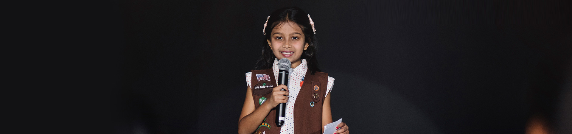 Brownie Girl Scout in uniform public speaking with microphone. 