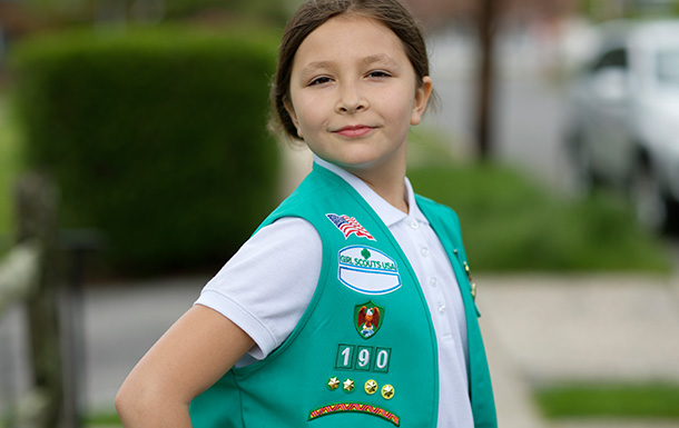 Junior Girl Scout smiling, showing off her vest with badges