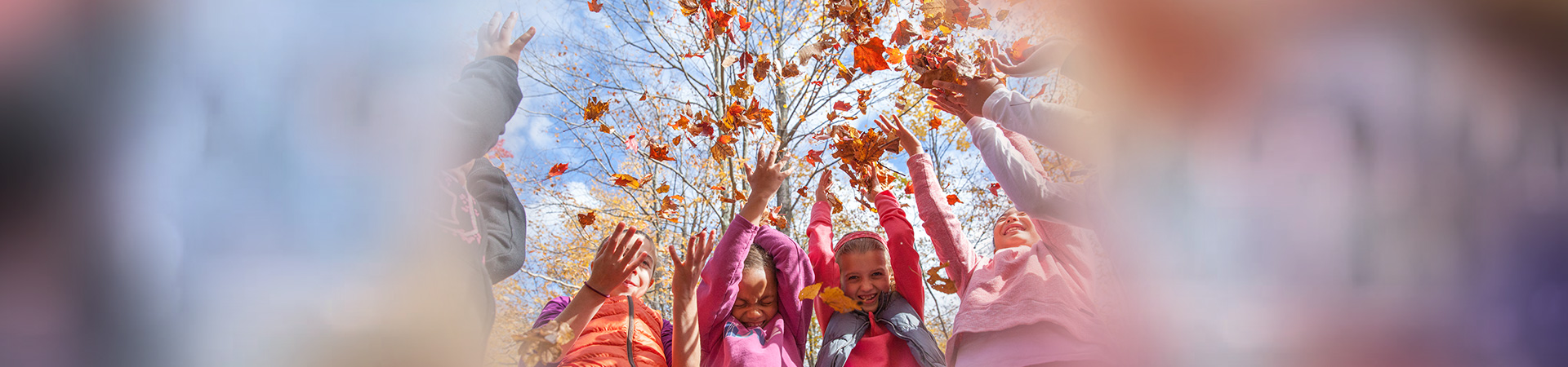 girls tossing fall leaves into the air 