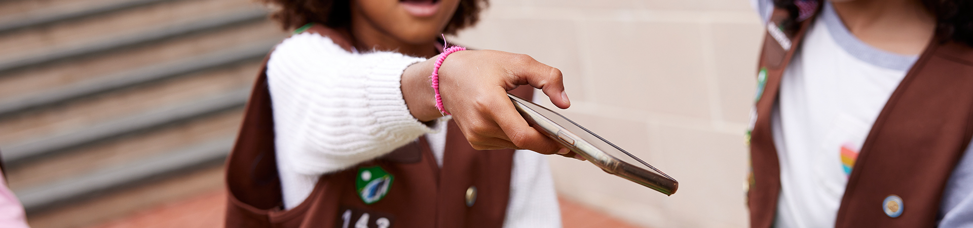  A Brownie Girl Scout holding out a phone to be scanned 