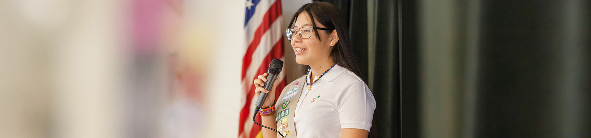  Senior Girl Scout standing at a lectern, speaking into a microphone 
