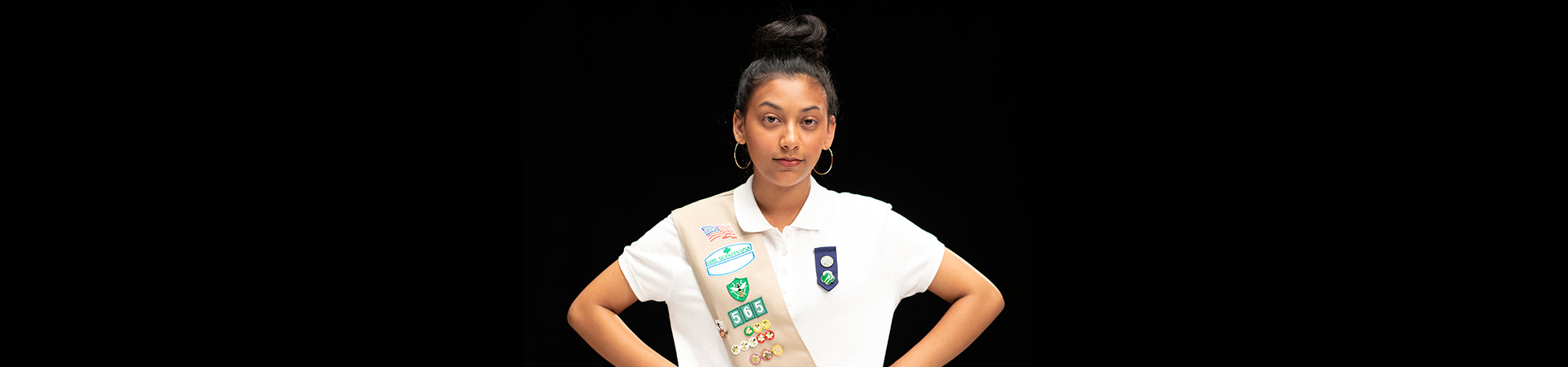  silver award girl scout standing with her hands on her hips in front of a black background 