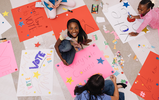 group of girls creating posters that encourage people to vote