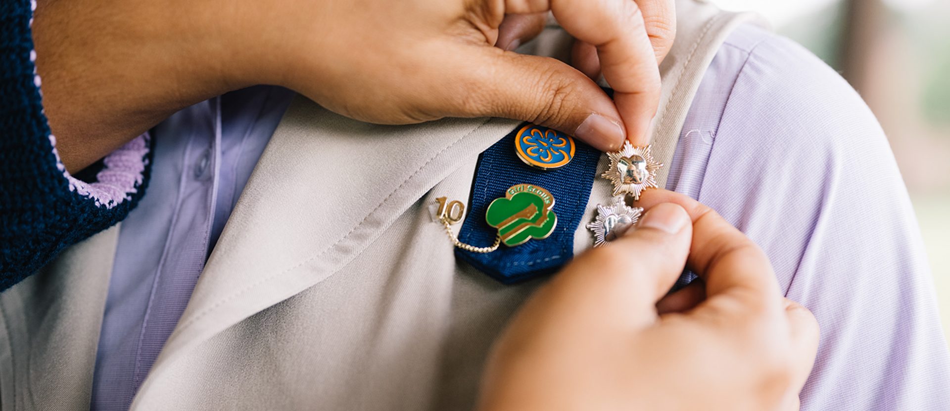 a volunteer pinning a Girl Scout with the Girl Scout Gold Award