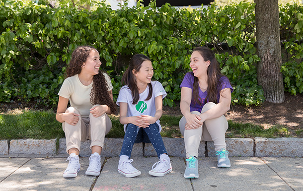 Three Ambassador Girl Scouts sitting outside talking and smiling