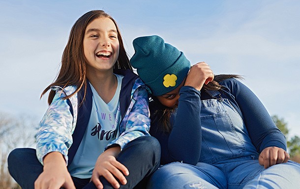 Two Girl Scouts laughing and sitting outside