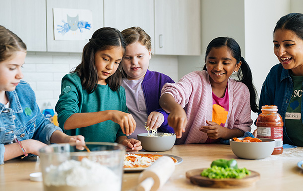 Group of younger girl scouts cooking in the kitchen.