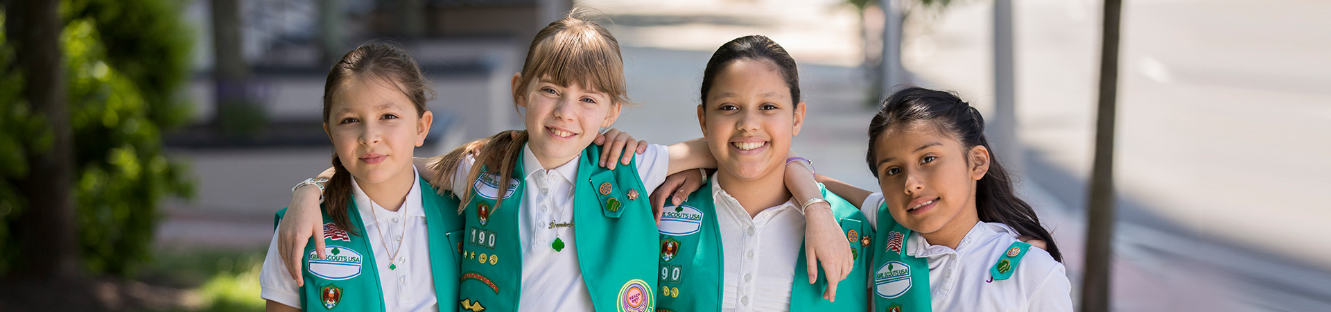  Four Junior Girl Scouts with their arms around each other smiling at the camera 