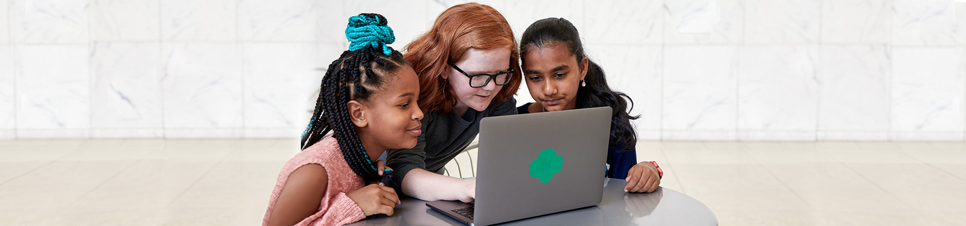  Three Girl Scouts gathered around a laptop 