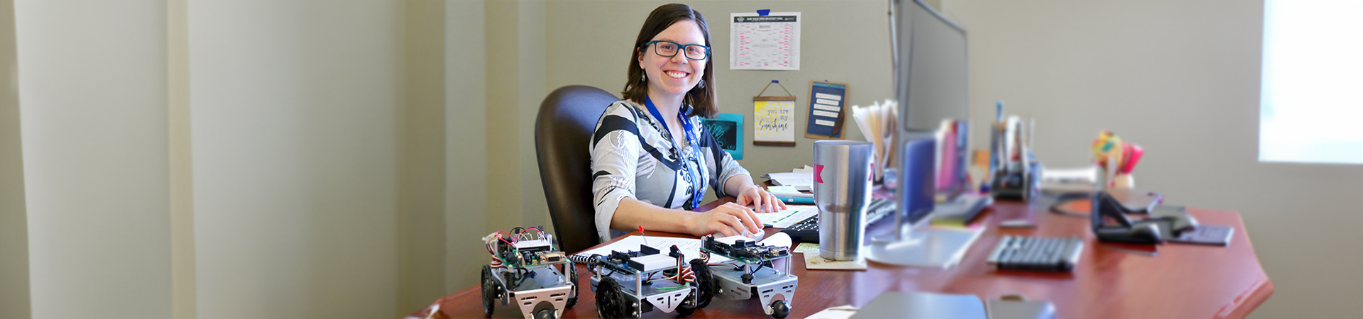  Callie Dean at her desk with some robots 