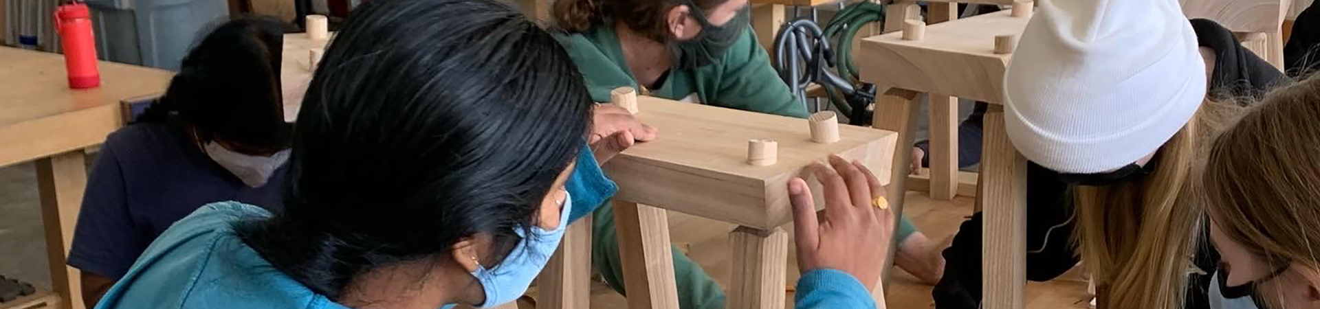  A group of Girl Scouts building stools in a woodshop 