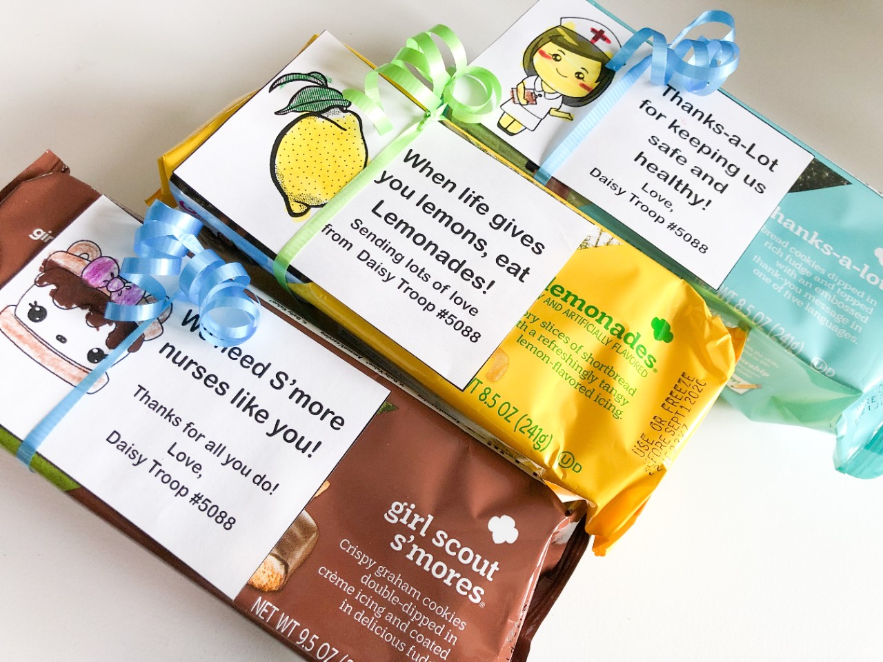 three wrapped boxes of Girl Scout Cookies with thank you notes attached