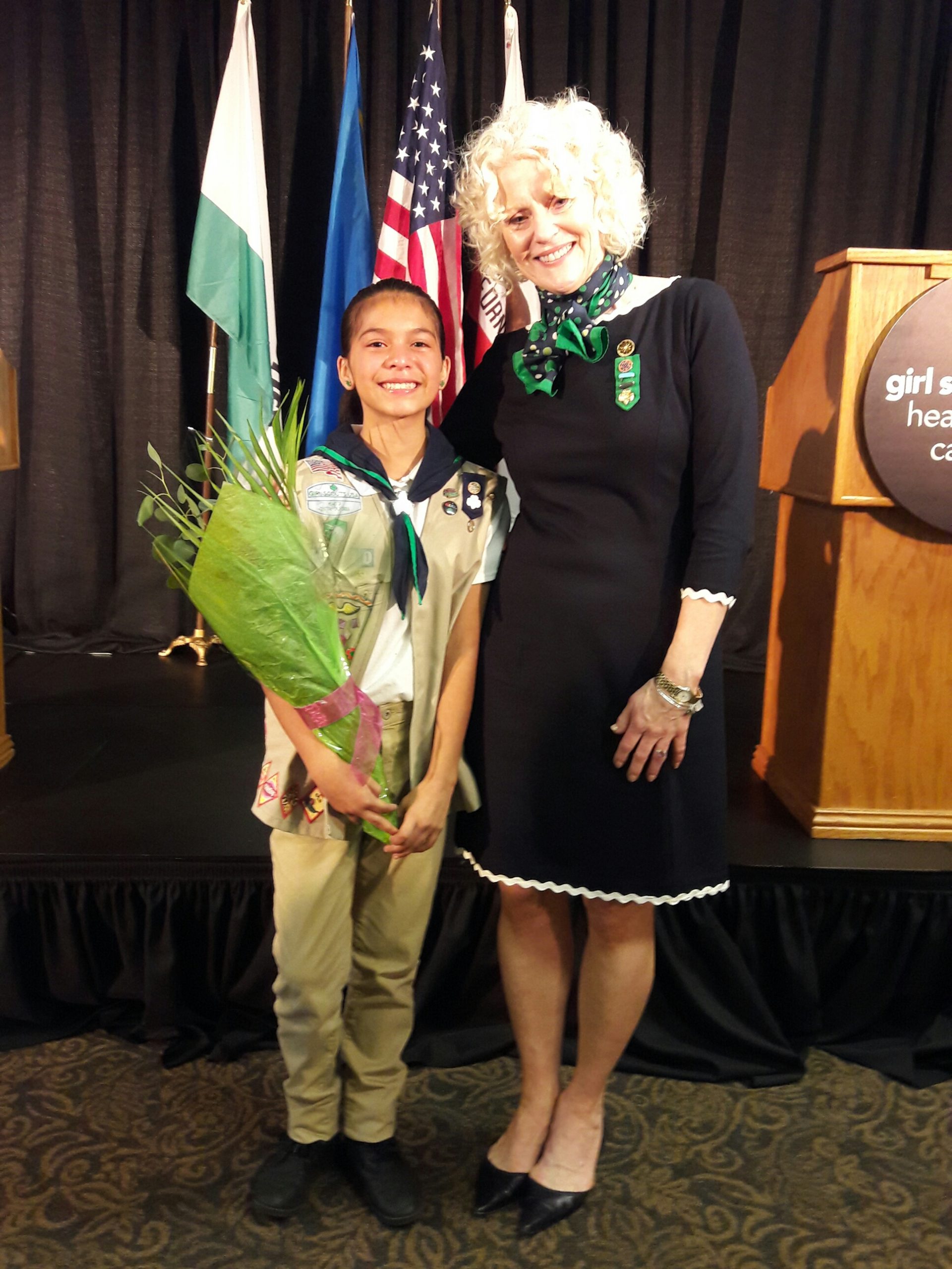 Taylor holding flowers and posing with Girl Scouts Heart of Central California CEO Linda Farley.