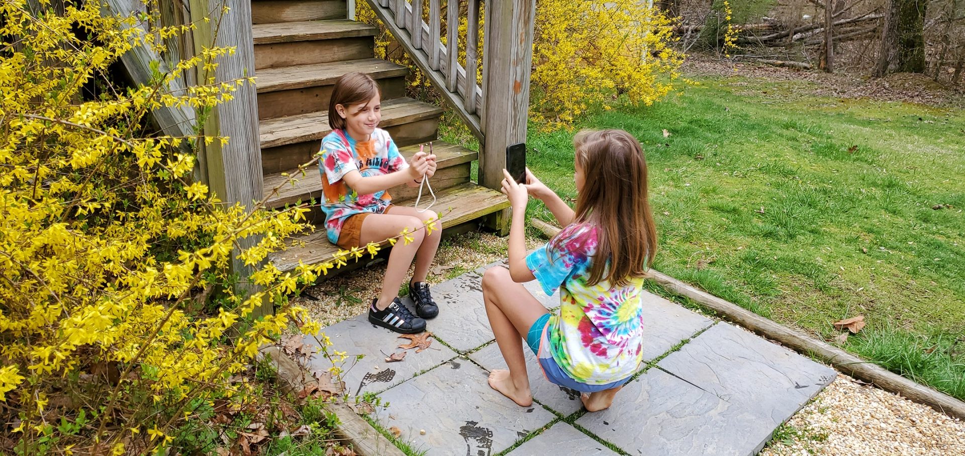  two girls in tie dye shirts filming a video about how to tie a knot 