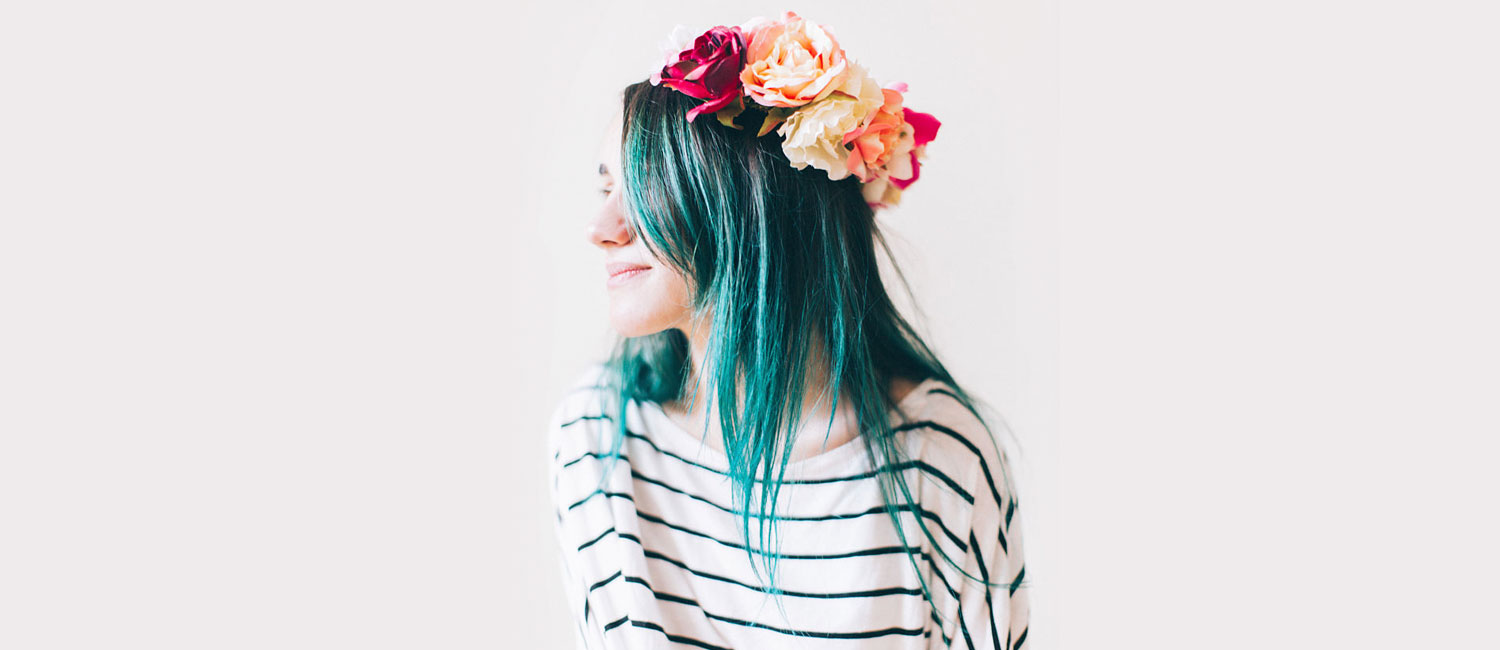  Young girl with a green dyed hair wearing a floral wreath. 