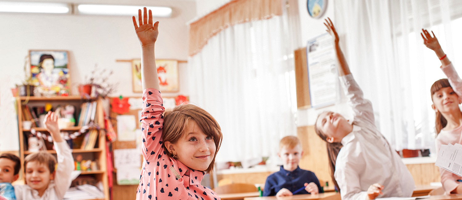  Pupils in the classroom raising hands. 