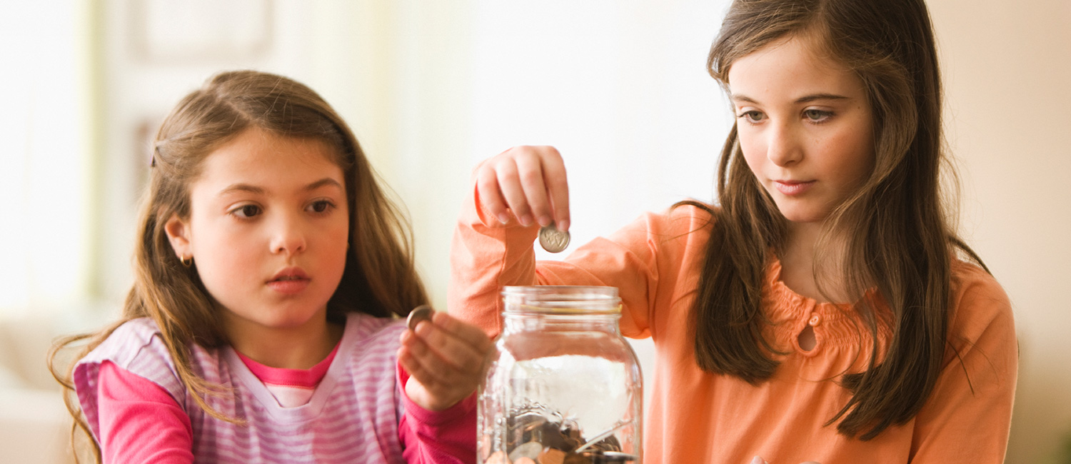  Sisters saving coins in a jar learning about financial literacy. 