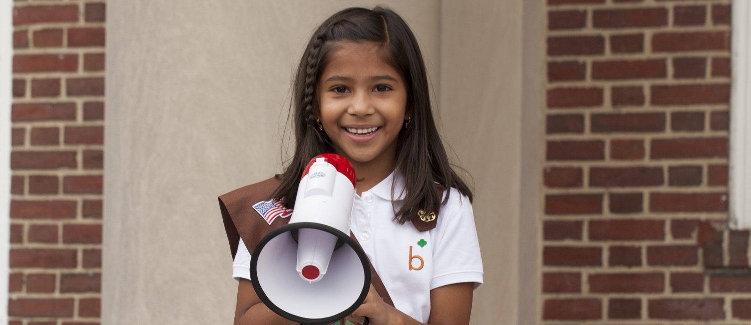  A Brownie holding a megaphone and smiling 