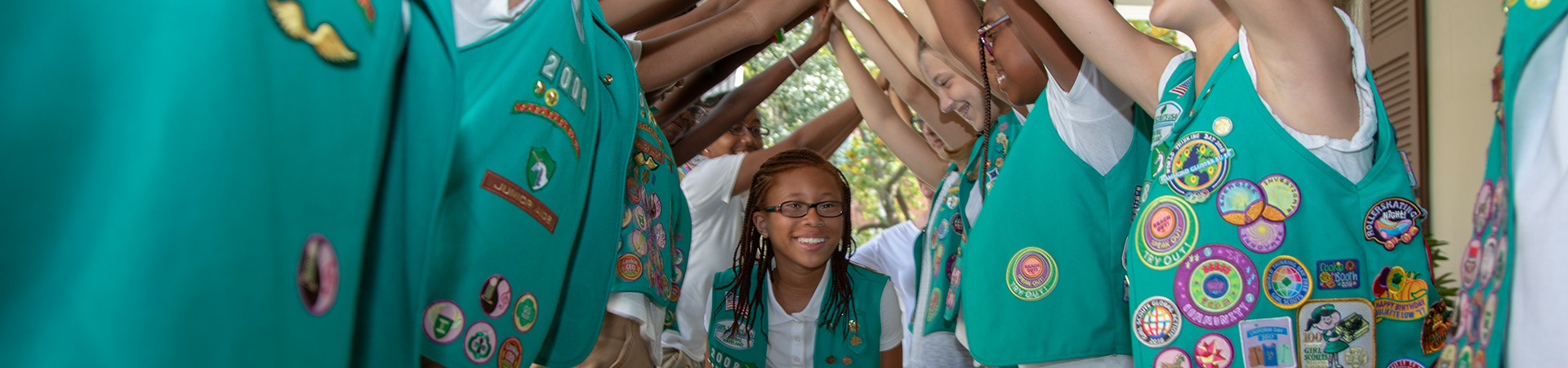  A troop of Junior Girl Scouts making a tunnel with their arms as one of them walks underneath 
