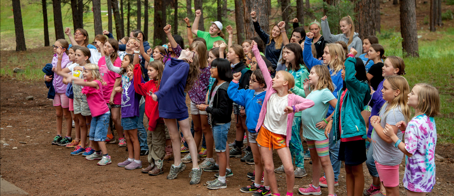  A large group of Girl Scouts at camp singing and dancing to a camp song 