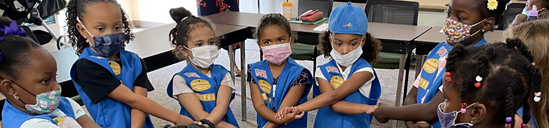  A group of Daisy Girl Scouts wearing masks while making the Girl Scout Friendship Circle 