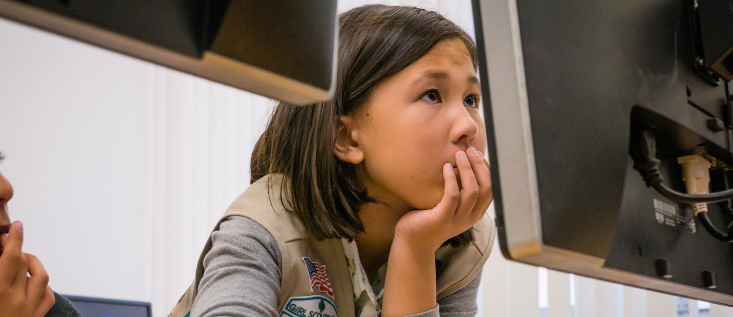  A Cadette Girl Scout looking intensely at a computer monitor 